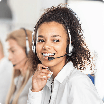 Smiling woman with headset working in a call center, with a colleague in the background.